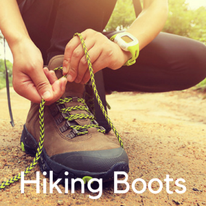 A woman tying hiking boots in a path