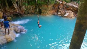 A woman swings from a rope and into a lagoon while on a Jamaican excursion adventure