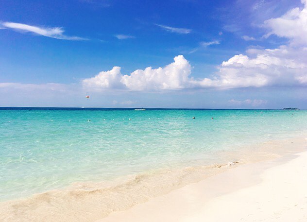 Families swim in the crystal blue waters of the world famous Seven Mile Beach of Negril, Jamaica 